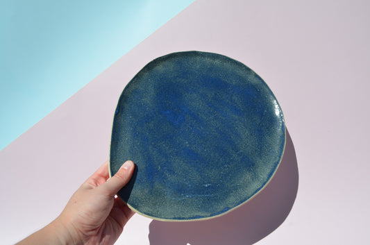 Picture of a large handmade organically shaped plate or platter, painted in a dark blue.