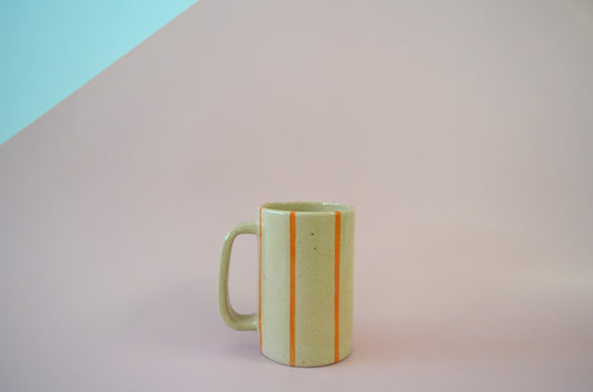 Picture of a handmade mug with a thin striped pattern painted in orange.